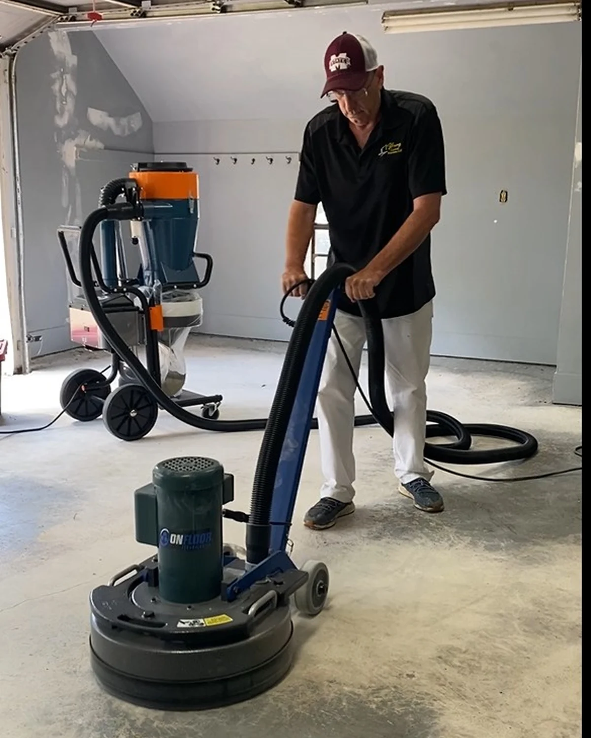 A worker preparing garage concrete with a floor grinding machine